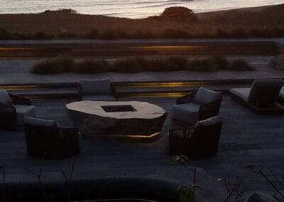 A sunset view over a beach with an outdoor seating area in the foreground.