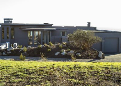 Modern coastal home with large windows and ocean view at sunset.